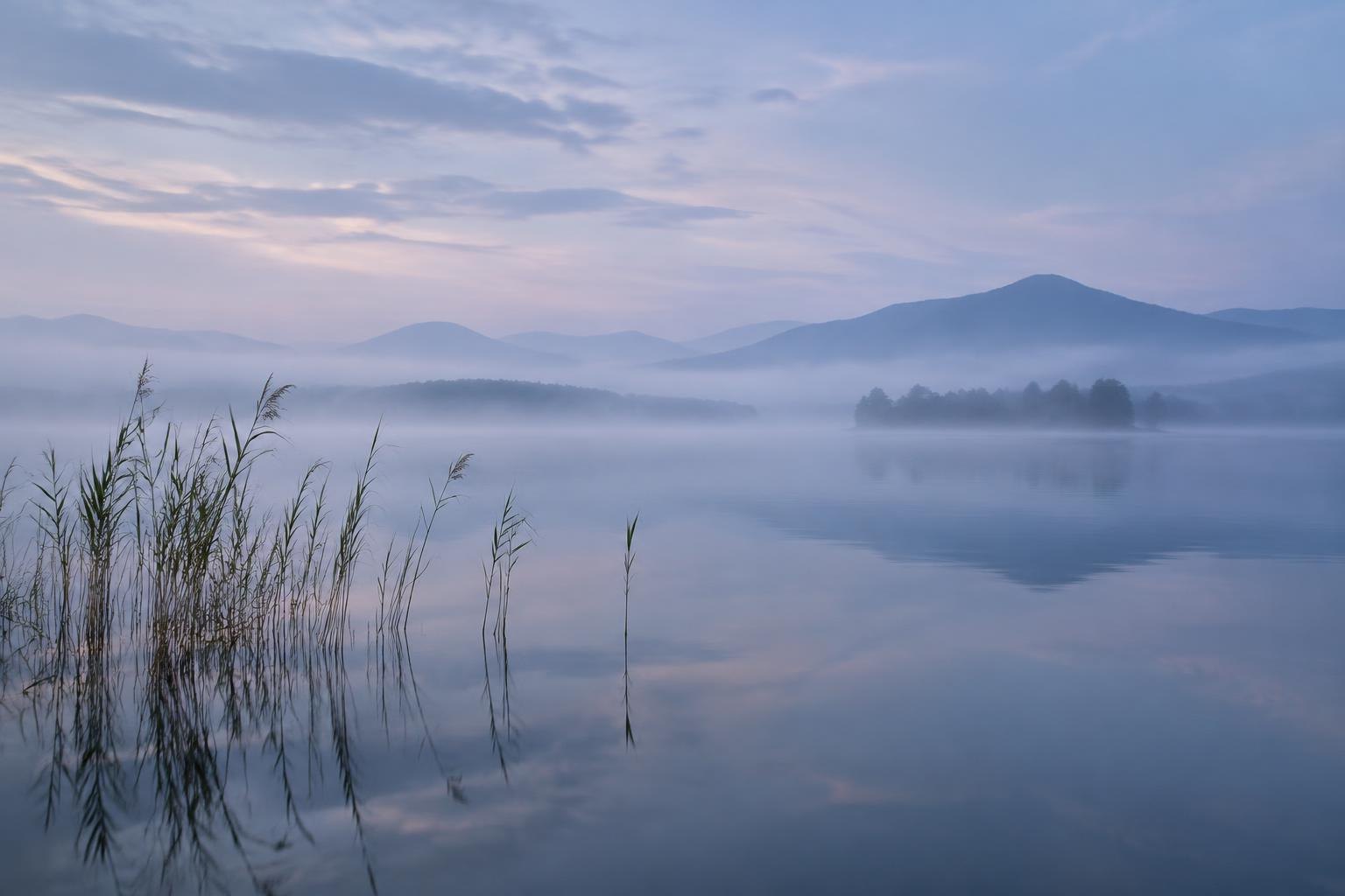 Lago y montañas entre niebla azulada